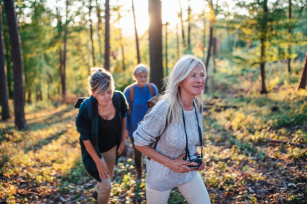 three women waling in the woods looking happy