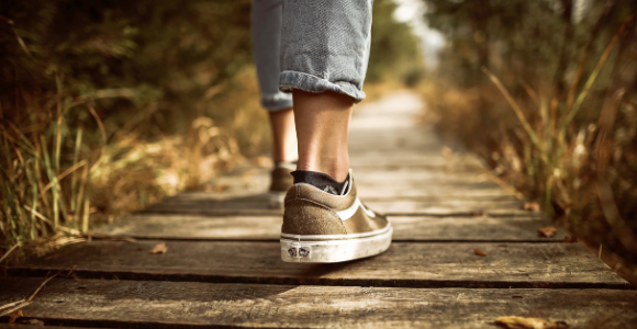 woman's shoes and lower legs walking on board walk.